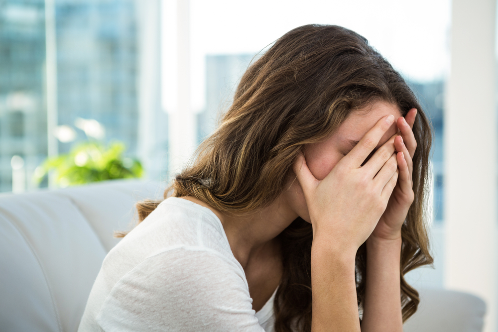 Sad woman holding her head on sofa