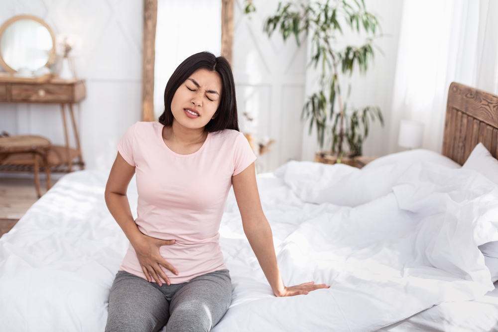 Girl Having Lower Abdominal Pain Sitting In Bed Indoors